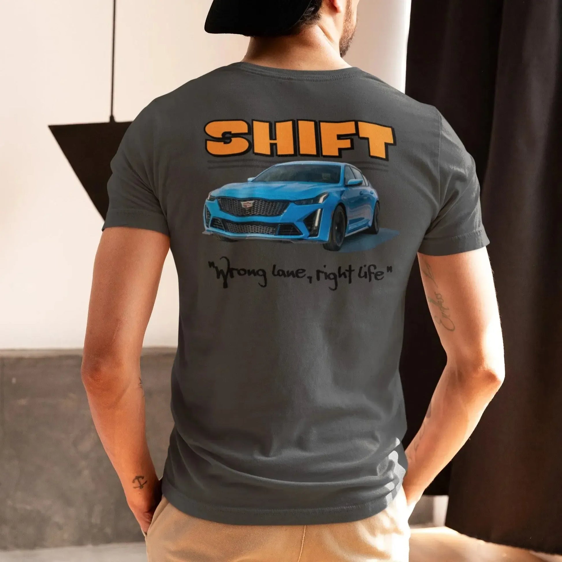 Person wearing a gray t-shirt with 'SHIFT' and a car graphic on the back, standing indoors.