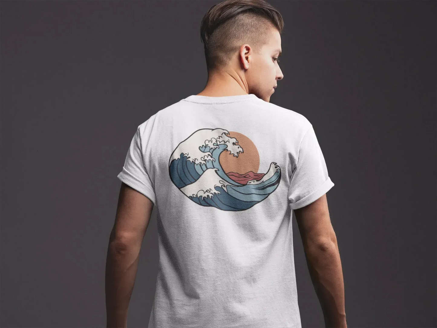 Person wearing a white t-shirt with a wave design on the back against a dark background