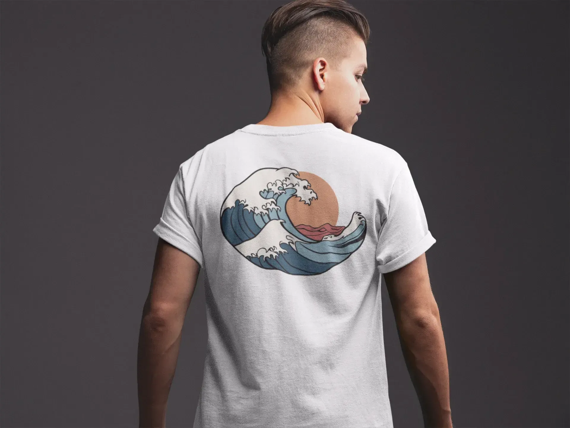 Person wearing a white t-shirt with a wave design on the back against a dark background